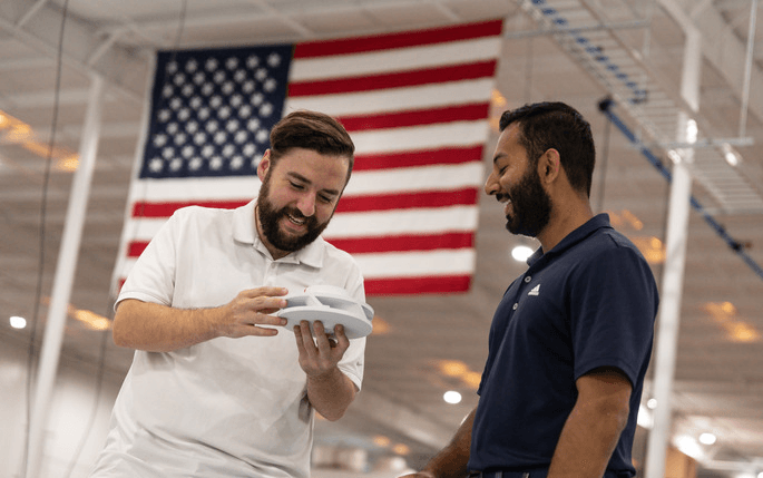 Two Endeavor 3D employees holding a 3D printed part