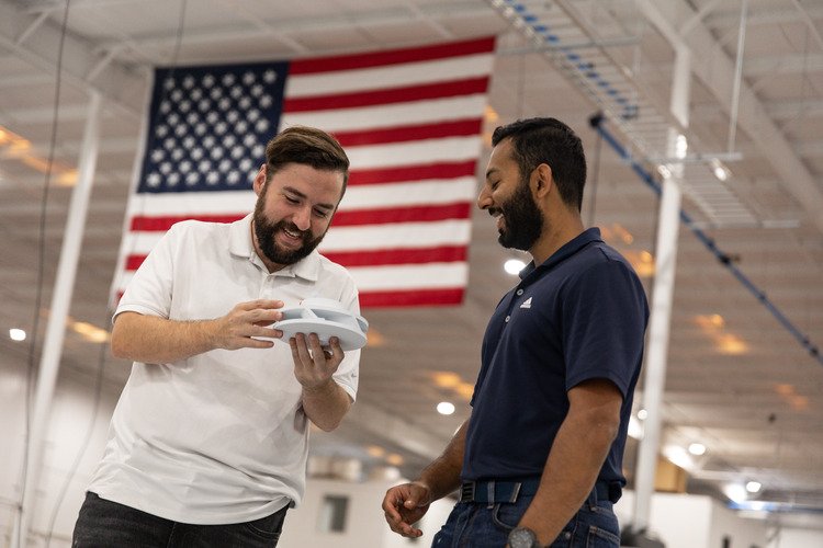 Multi Jet Fusion Design Guidelines Two Endeavor 3D employees holding a pa 12 white 3D printed part