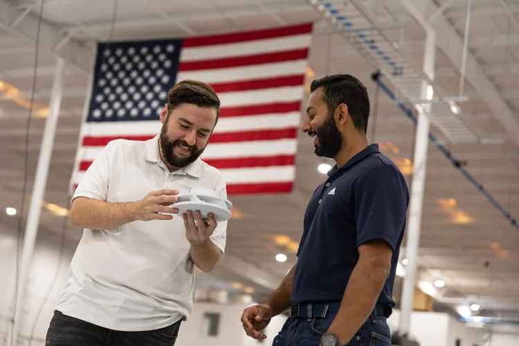 Multi Jet Fusion Design Guidelines Two Endeavor 3D employees holding a pa 12 white 3D printed part