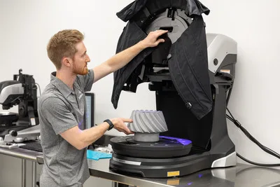 Man in scanning 3D printed polymer part with quality control equipment