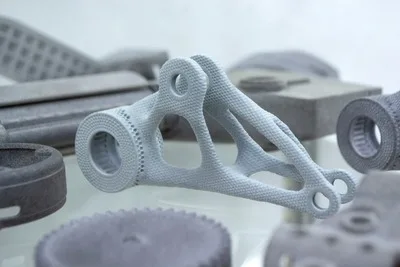 A MJF PA 12 part on a table with other 3d printed parts