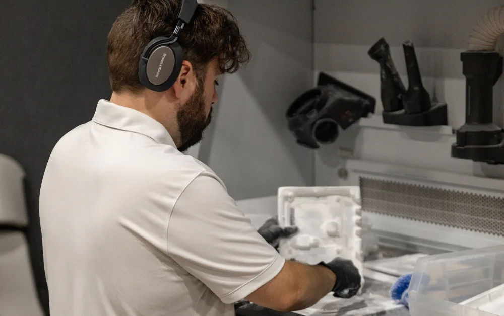 Sustainable MJF 3D Printing Depowdering Endeavor 3D employee using a depowdering instrument to remove excess powder from an MJF 3D Printing part